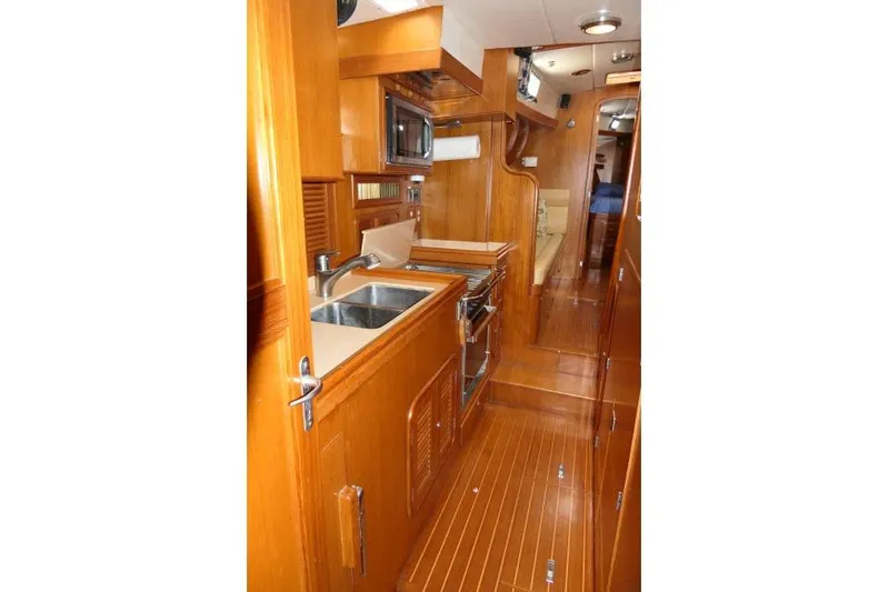 Peregrine Yacht Photos Pics Interior of 2002 Tayana 460 Vancouver Pilothouse with wooden cabinetry and modern kitchen amenities.
