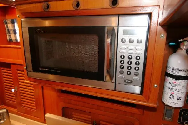 Peregrine Yacht Photos Pics Microwave in 2002 Tayana 460 Vancouver Pilothouse kitchen, featuring wooden cabinetry and fire extinguisher.