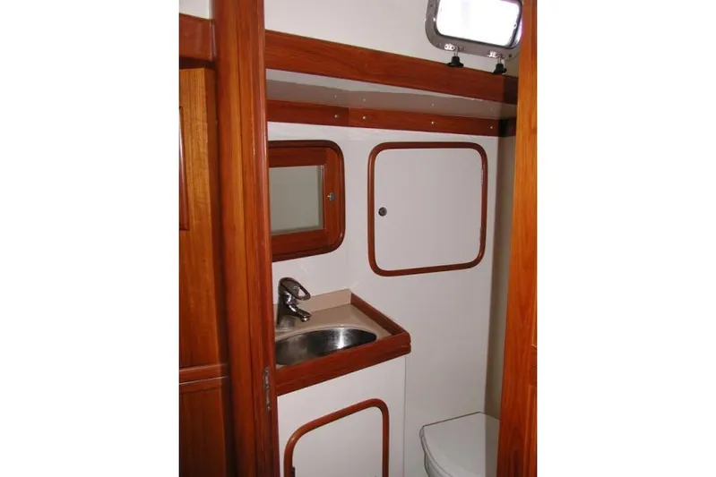Peregrine Yacht Photos Pics 2002 Tayana 460 Vancouver Pilothouse bathroom with sink, mirror, and wooden accents.