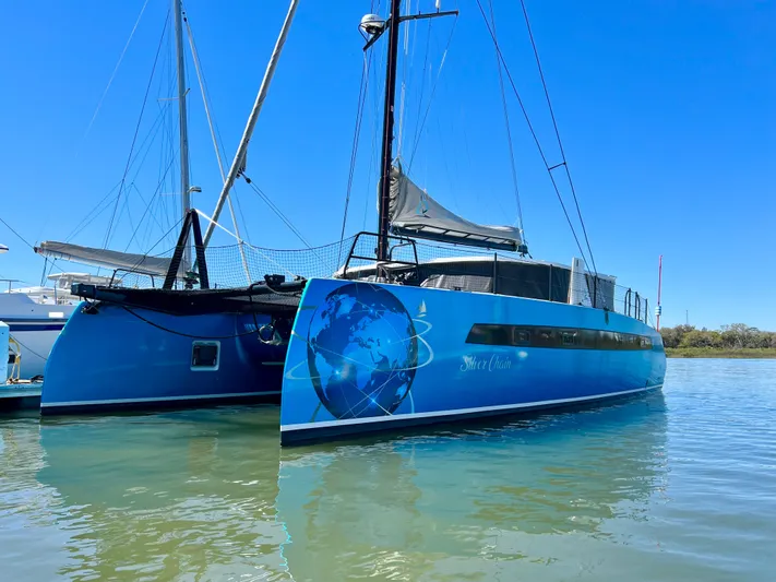 Silver Chain Yacht Photos Pics 2024 Balance 442 catamaran with blue globe design, docked on calm water under clear sky.