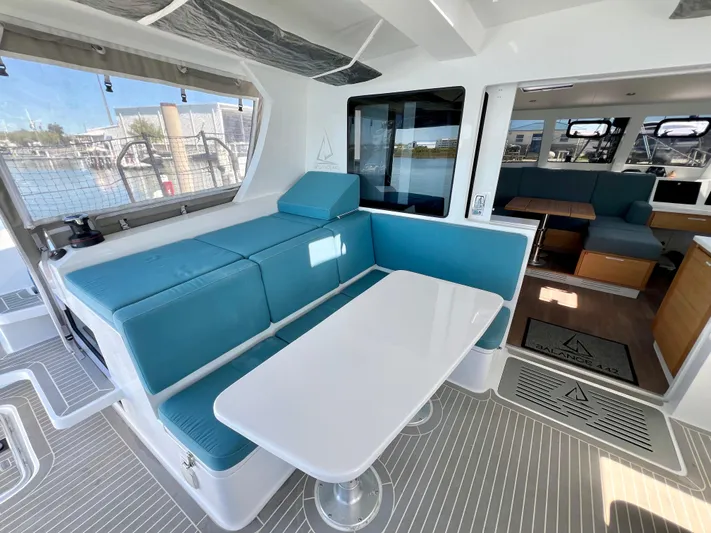 Silver Chain Yacht Photos Pics 2024 Balance 442 yacht interior with blue seating and white table, docked at marina.