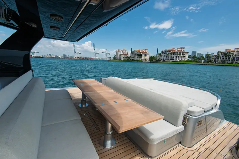 Ciao L Yacht Photos Pics Luxurious 2022 SACS Rebel 55 yacht deck with seating, overlooking waterfront buildings.