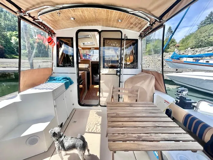 Denial Yacht Photos Pics 2012 Cutwater C-28 boat interior with wooden table, chairs, and a small dog.