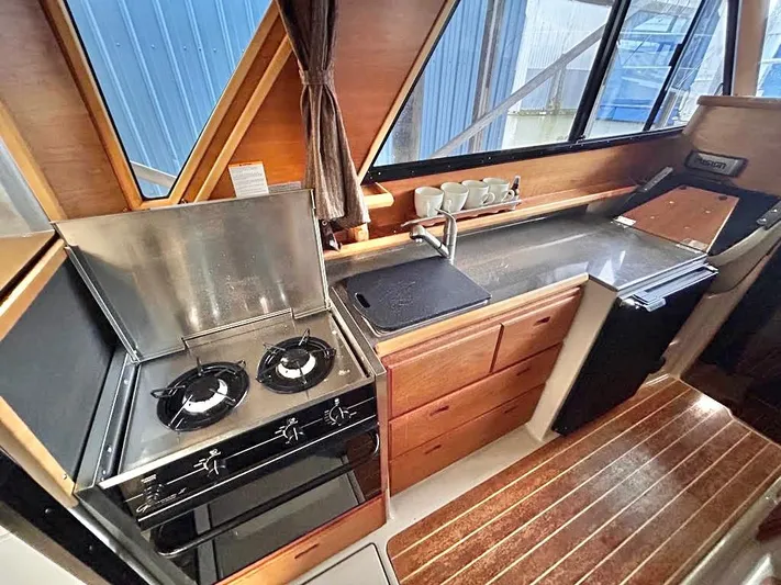 Denial Yacht Photos Pics Interior of 2012 Cutwater C-28 boat kitchen with stove, sink, and wooden cabinetry.