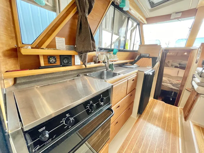 Denial Yacht Photos Pics Interior of 2012 Cutwater C-28 boat featuring kitchen with stove, sink, and wooden cabinetry.