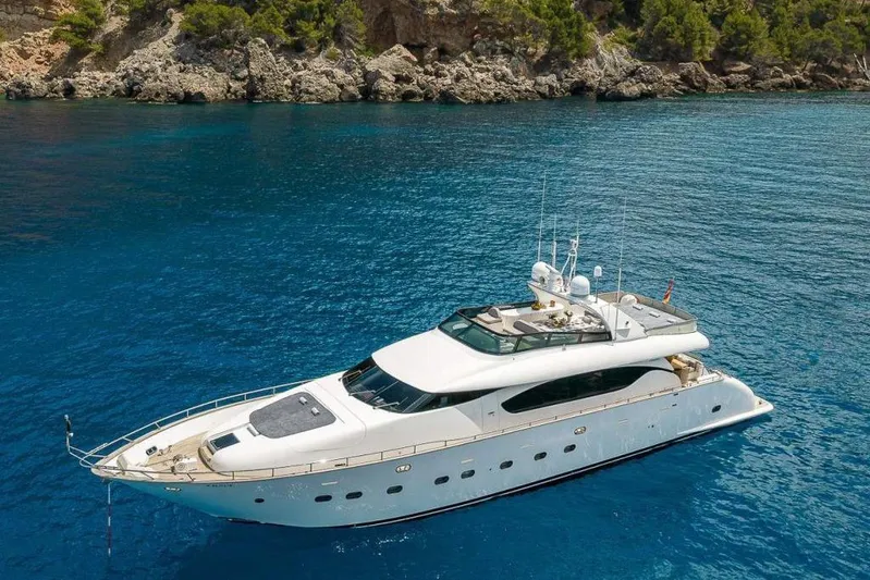 Pobedy I Yacht Photos Pics Luxurious 2004 Maiora 26.5 yacht anchored in clear blue waters near rocky coastline.