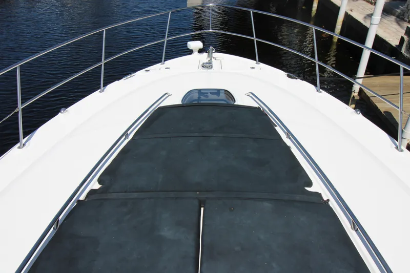 Rowdy Rio Yacht Photos Pics 2008 Sea Ray 44 Sundancer yacht bow with sunpad, docked by calm water.