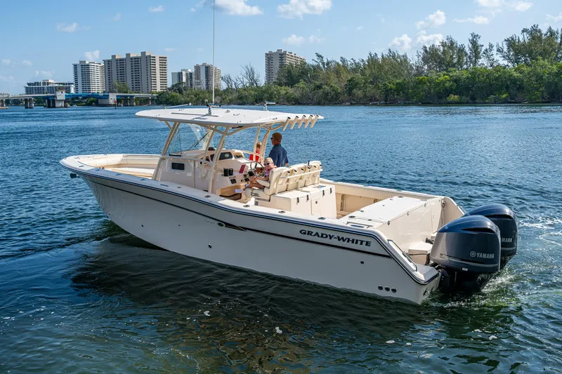  Yacht Photos Pics 2012 Grady-White 336 boat cruising on a sunny day with cityscape in the background.