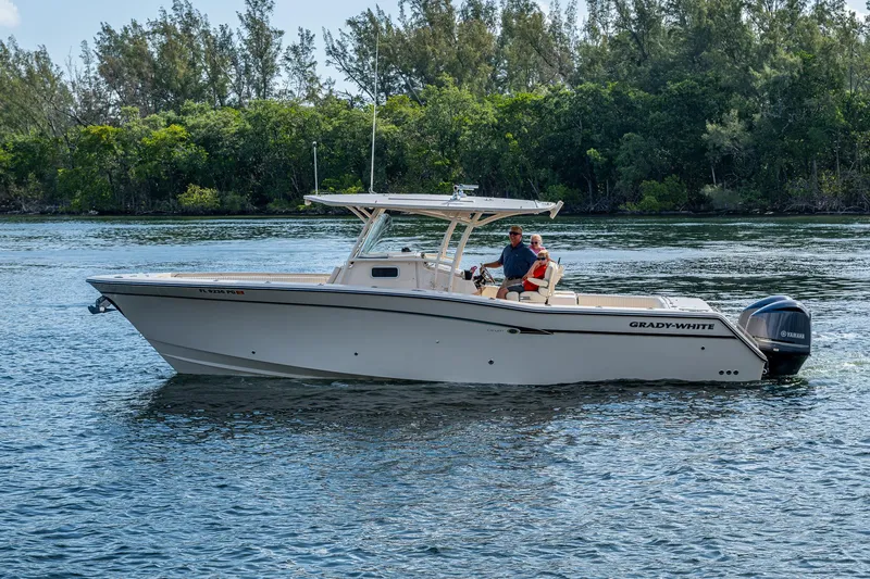 Yacht Photos Pics 2012 Grady-White 336 boat cruising on a calm river with lush greenery in the background.