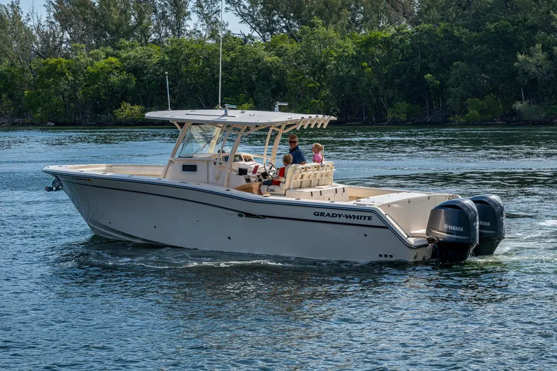  Yacht Photos Pics 2012 Grady-White 336 boat cruising on a calm lake with lush greenery in the background.