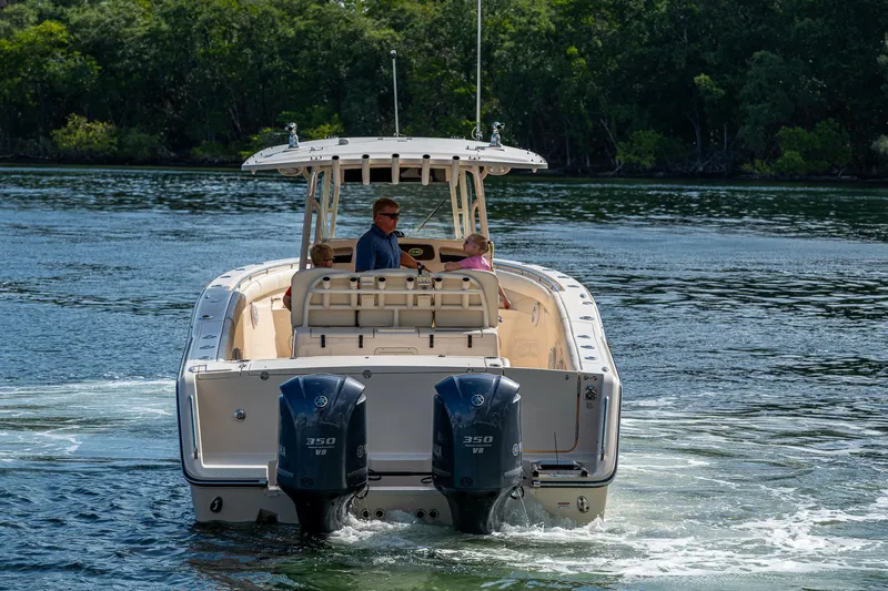  Yacht Photos Pics 2012 Grady-White 336 boat cruising on a calm lake with lush green trees.