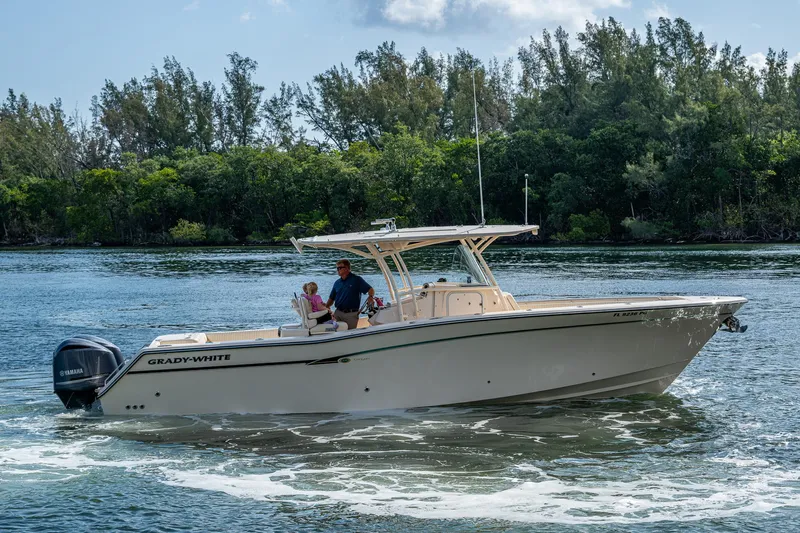  Yacht Photos Pics 2012 Grady-White 336 boat cruising on a scenic waterway with lush greenery in the background.