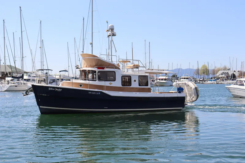 Yellow Jacket Yacht Photos Pics 2020 Ranger Tugs R-31 CB boat cruising in a marina with sailboats in the background.