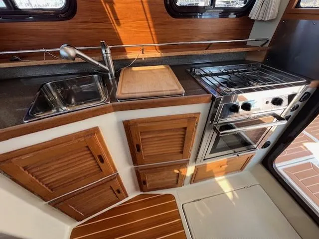 Yellow Jacket Yacht Photos Pics 2020 Ranger Tugs R-31 CB kitchen with stove, sink, and wooden cabinetry.