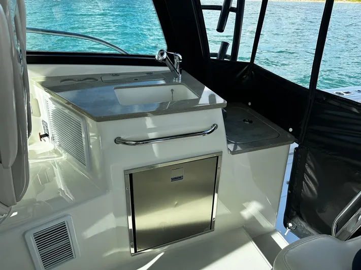  Yacht Photos Pics 2022 Boston Whaler 345 Conquest interior with sink and storage, overlooking blue water.