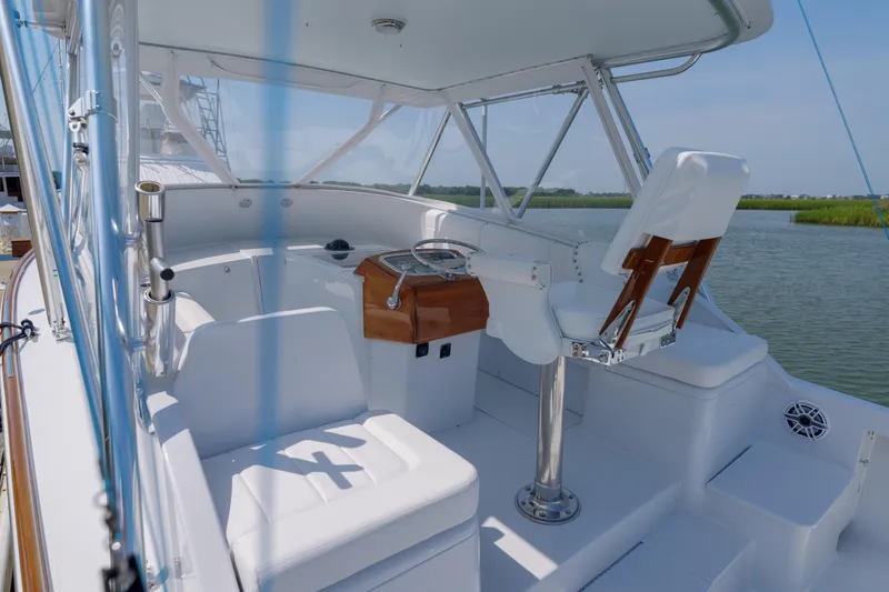 Enticer Yacht Photos Pics 1998 Gamefisherman Enticer boat helm with white seating and steering wheel, docked by calm waters.