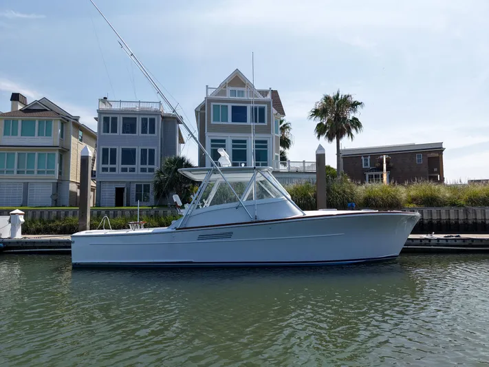 Enticer Yacht Photos Pics 1998 Gamefisherman Enticer boat docked near waterfront homes, under a clear blue sky.