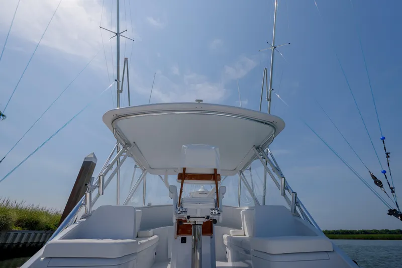 Enticer Yacht Photos Pics 1998 Gamefisherman Enticer boat with white seating and fishing rods under a clear blue sky.