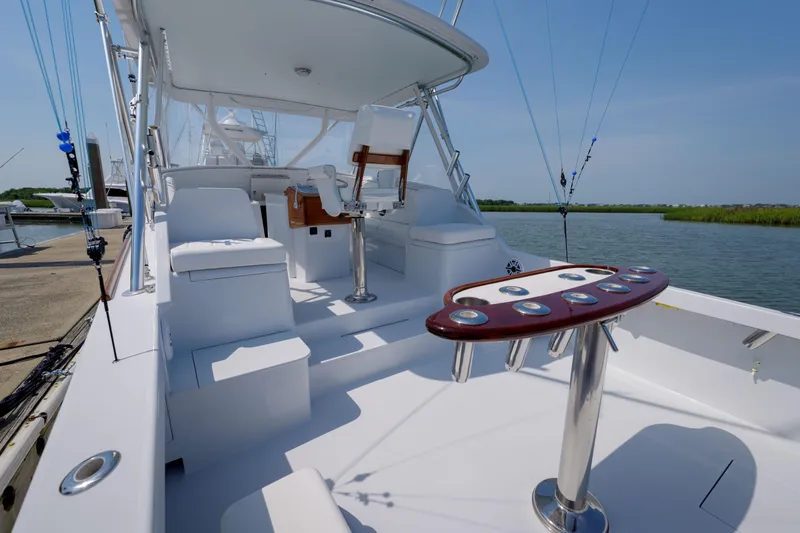 Enticer Yacht Photos Pics 1998 Gamefisherman Enticer boat with fishing rods, docked by a serene waterway.