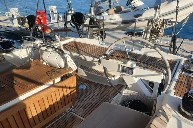  Yacht Photos Pics 2013 Jeanneau 57 yacht cockpit with wooden deck and steering wheel, docked by the water.