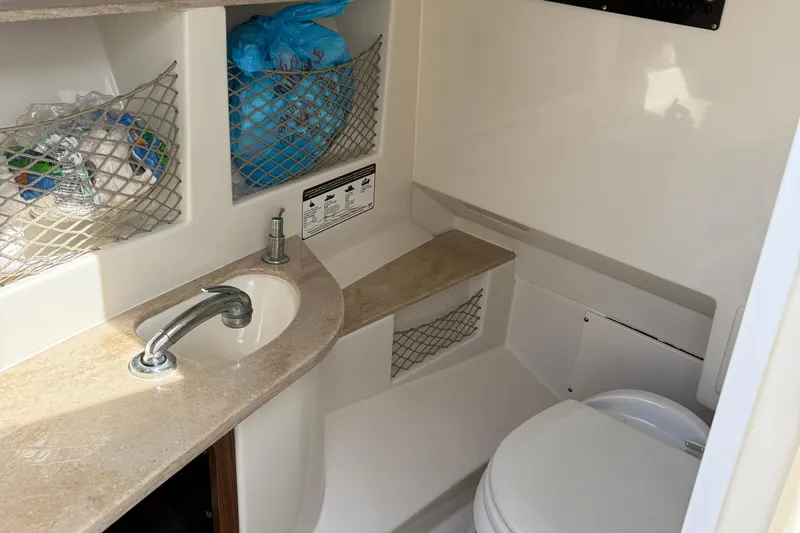  Yacht Photos Pics 2016 Sailfish 325 DC boat bathroom with sink, storage nets, and toilet.