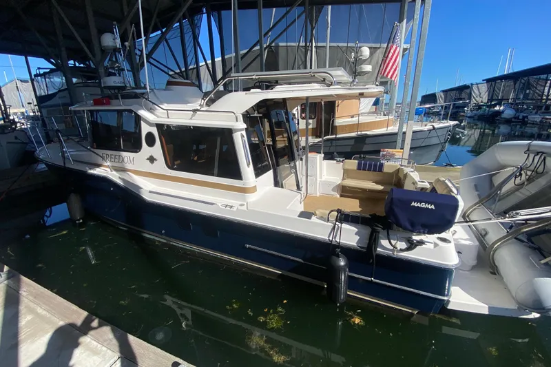 Yacht Photos Pics 2019 Ranger Tugs R-29 S docked in a marina, featuring a spacious deck and American flag.
