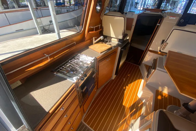  Yacht Photos Pics 2019 Ranger Tugs R-29 S interior with wood finish, compact kitchen, and seating area.