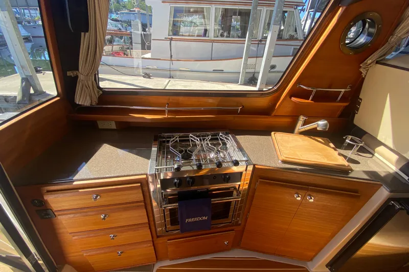  Yacht Photos Pics 2019 Ranger Tugs R-29 S interior kitchen with stove, sink, and wooden cabinetry.