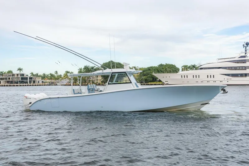 Rule #1 Yacht Photos Pics 2023 Yellowfin 42 Offshore boat cruising on a calm waterway, with luxury yachts in the background.