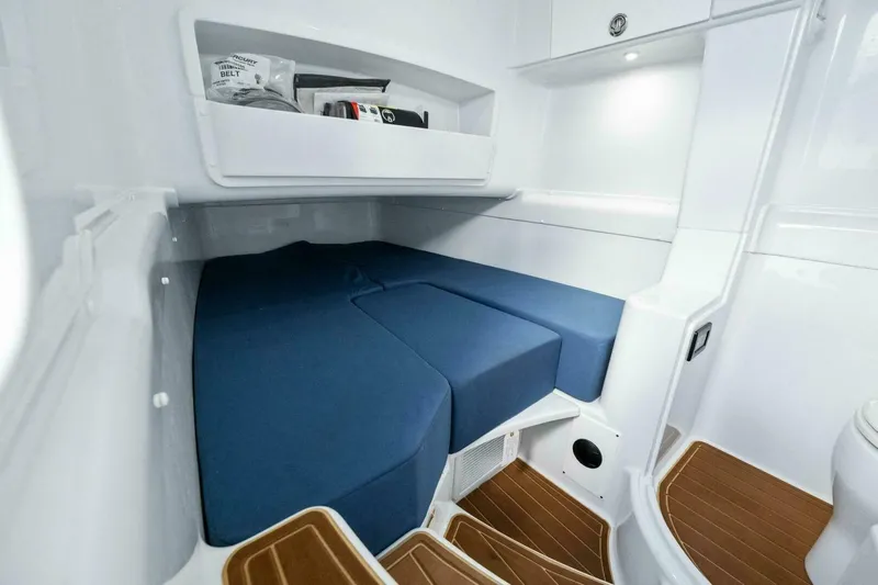 Rule #1 Yacht Photos Pics 2023 Yellowfin 42 Offshore cabin interior with blue seating and wooden flooring.