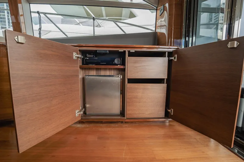 Endeavor Yacht Photos Pics Open wooden cabinet on 2019 Princess F55 yacht, revealing storage and mini fridge.