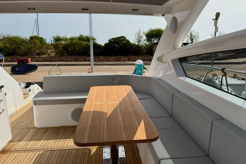 Dena Yacht Photos Pics Luxurious seating area on 2021 Airon Cinquanta 50 yacht with wooden table and cushions.