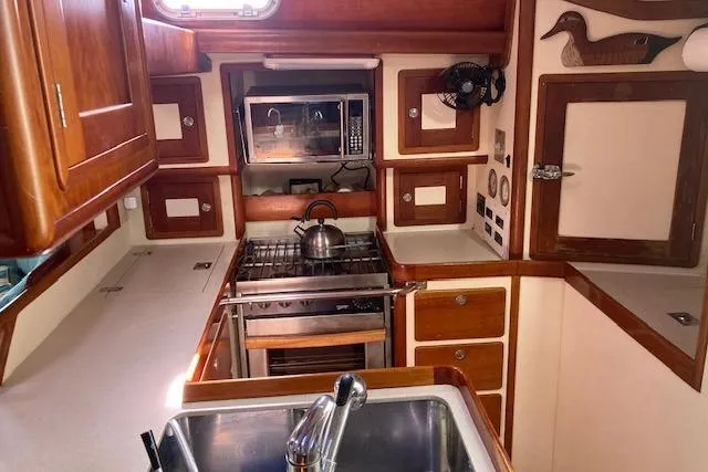 Tumblehome Yacht Photos Pics 1999 Little Harbor 51 Pilothouse kitchen with wooden cabinetry, stove, and sink.