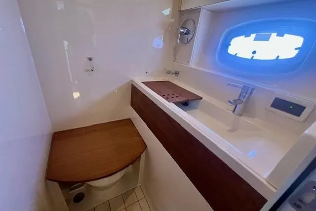 Stay Loose Yacht Photos Pics 2013 Sea Ray 410 Sundancer bathroom with sink, toilet, and porthole window.