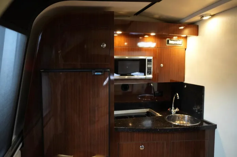  Yacht Photos Pics 2014 Regal 38 Express yacht interior kitchen with microwave, sink, and wood cabinetry.
