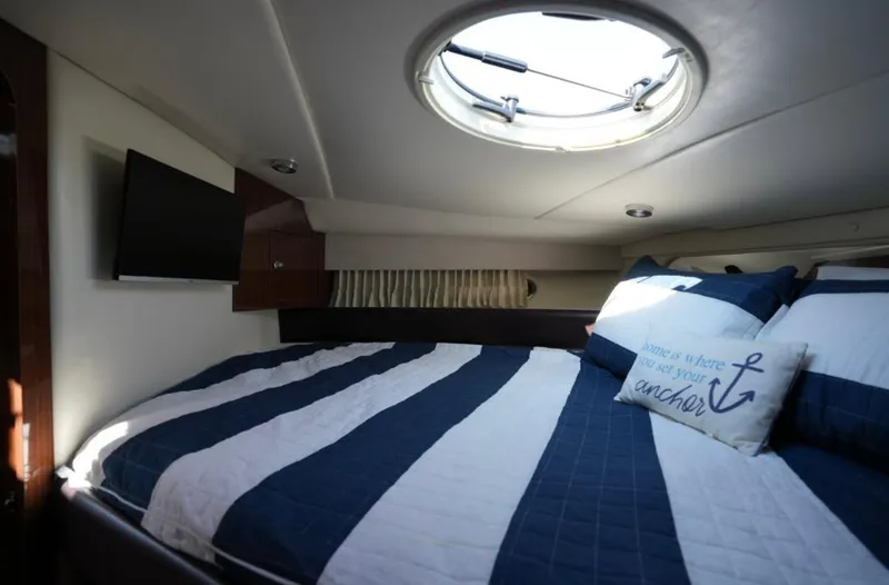  Yacht Photos Pics 2014 Regal 38 Express cabin with striped bedding, porthole, and TV.