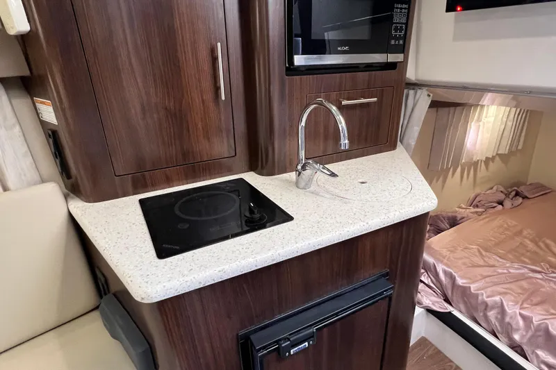  Yacht Photos Pics 2018 Regal 28 Express boat interior with kitchenette, featuring stove, sink, and microwave.