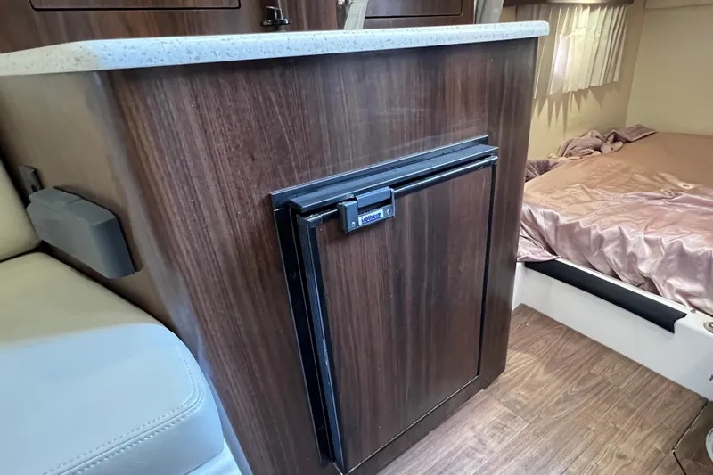  Yacht Photos Pics 2018 Regal 28 Express interior with wood cabinetry and compact fridge.