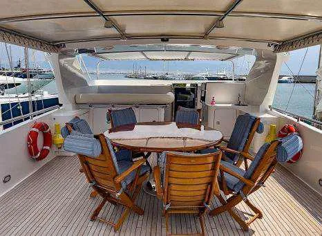  Yacht Photos Pics Codecasa 32m 1999 yacht deck with wooden dining table and chairs, marina view.