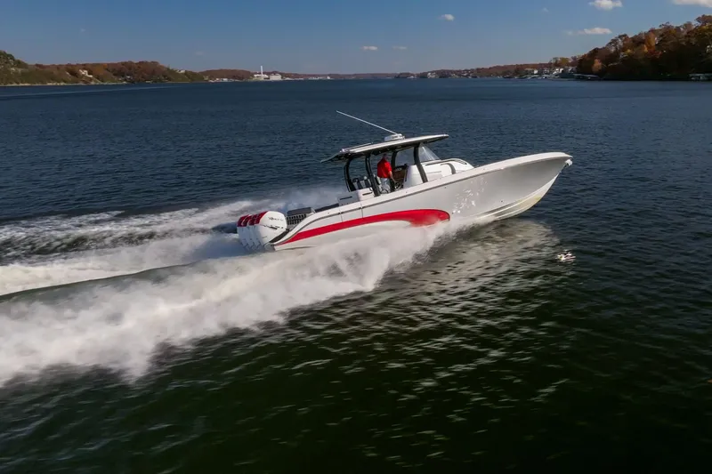  Yacht Photos Pics 2020 Fountain 43 NX speedboat cruising on a scenic lake under a clear blue sky.
