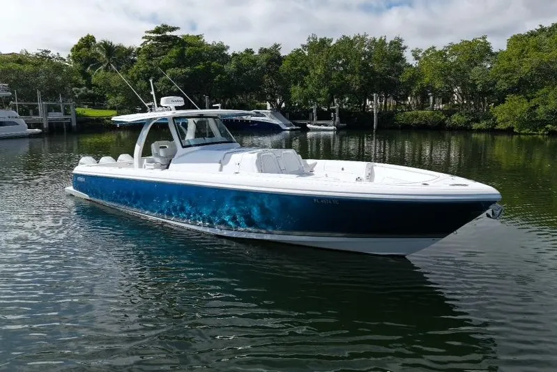 Yacht Photos Pics 2022 Intrepid 407 Panacea boat on calm water, surrounded by lush greenery.