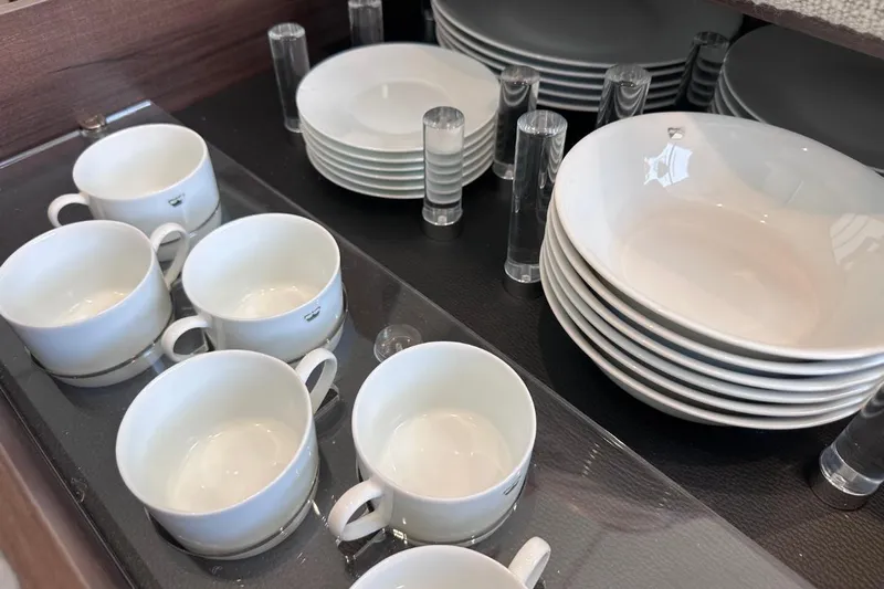  Yacht Photos Pics White ceramic cups and plates neatly arranged in a cabinet on a Princess S62 yacht.