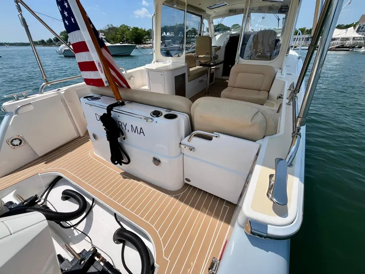 Waterlee Yacht Photos Pics 2019 MJM 35z boat with spacious deck, comfortable seating, and American flag, docked in sunny marina.