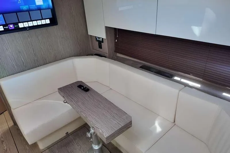  Yacht Photos Pics 2024 Sessa Marine C44 Cruiser interior with white seating, wooden table, and wall-mounted TV.