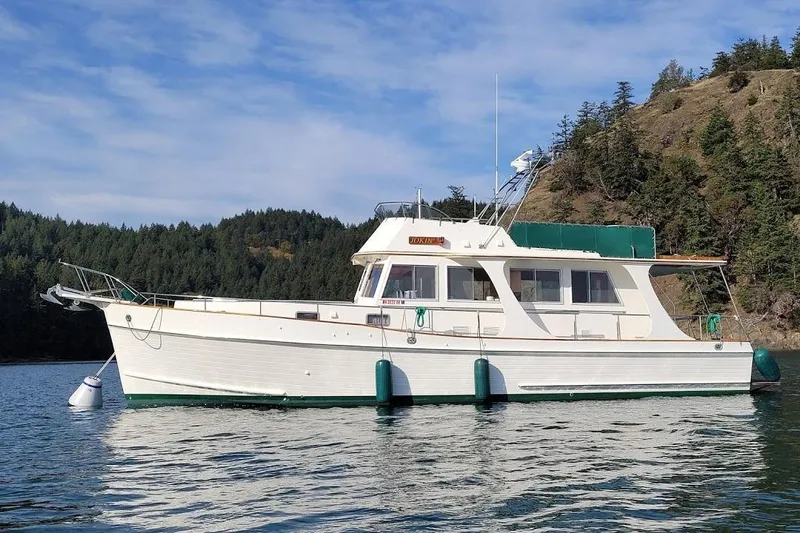 Goodlife Yacht Photos Pics 1998 Grand Banks 46 Europa yacht on calm water, surrounded by forested hills.