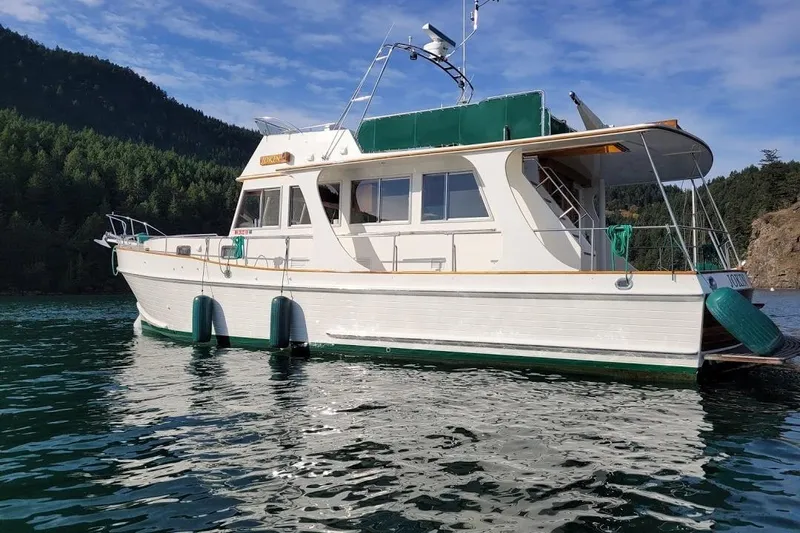 Goodlife Yacht Photos Pics 1998 Grand Banks 46 Europa yacht on serene water with forested hills in the background.
