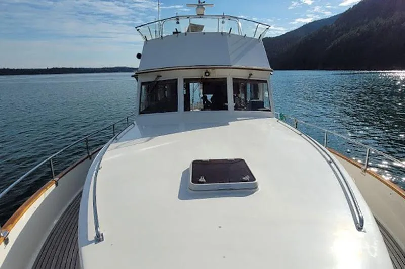 Goodlife Yacht Photos Pics 1998 Grand Banks 46 Europa yacht cruising on serene waters with scenic mountain backdrop.