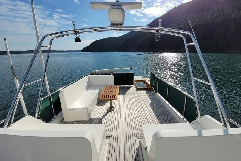 Goodlife Yacht Photos Pics 1998 Grand Banks 46 Europa yacht deck with seating, overlooking serene water and forested hills.
