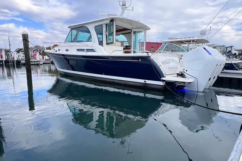 Wally World Yacht Photos Pics 2024 Back Cove 39O boat docked in marina, reflecting on calm water under cloudy sky.