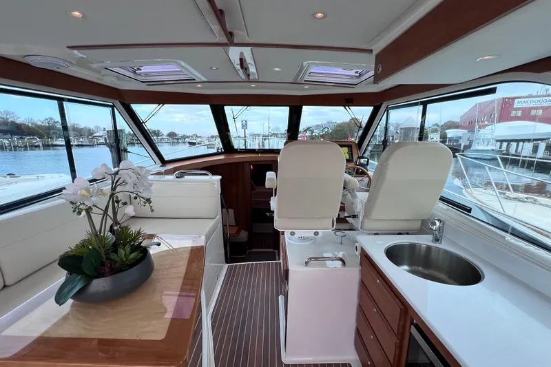 Wally World Yacht Photos Pics 2024 Back Cove 39O yacht interior with helm, seating, and kitchenette overlooking marina.